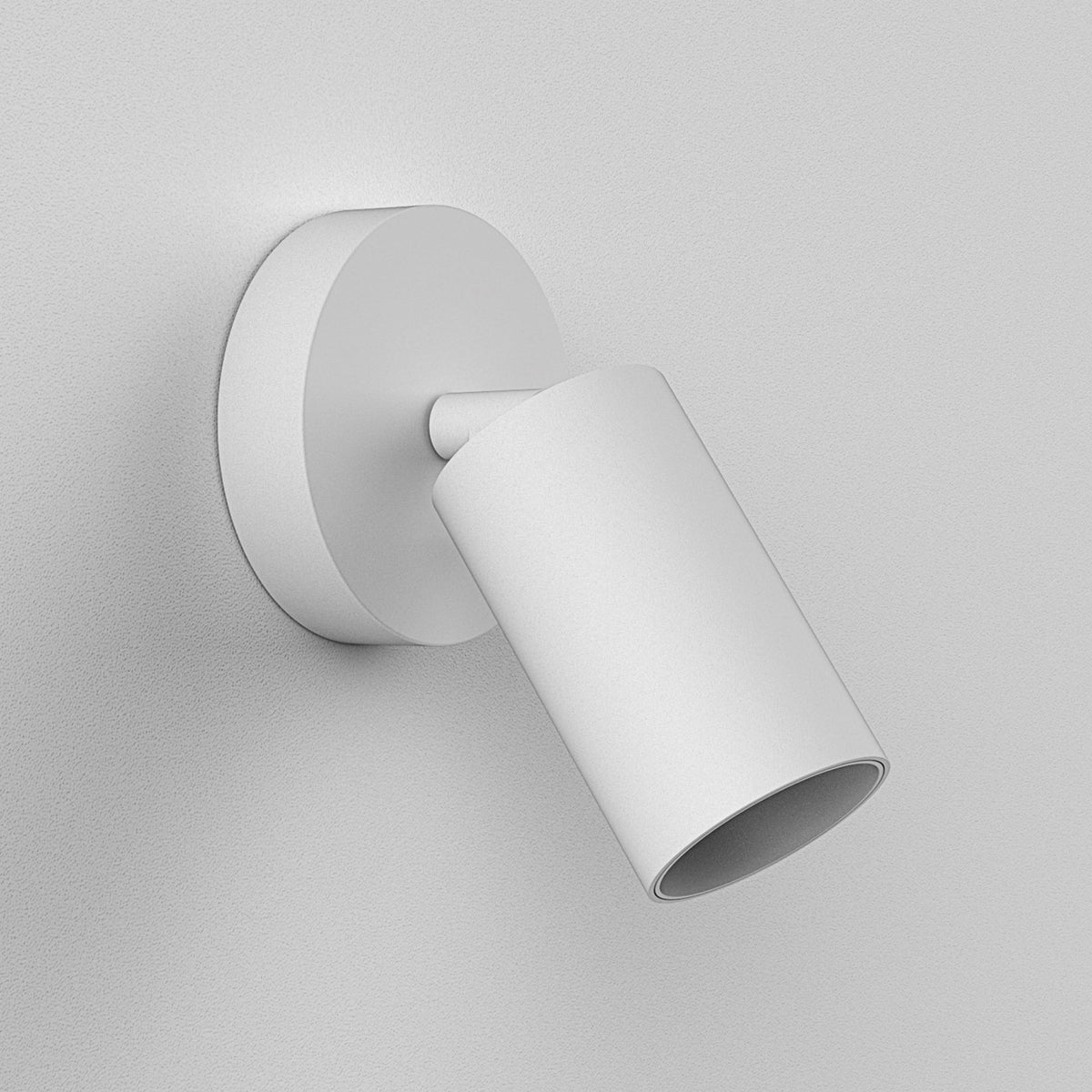 White cylindrical wall light with a circular base, angled downwards on a textured white wall