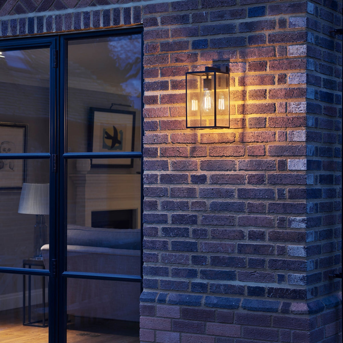 Black rectangular outdoor wall light with clear glass panels and an exposed filament bulb