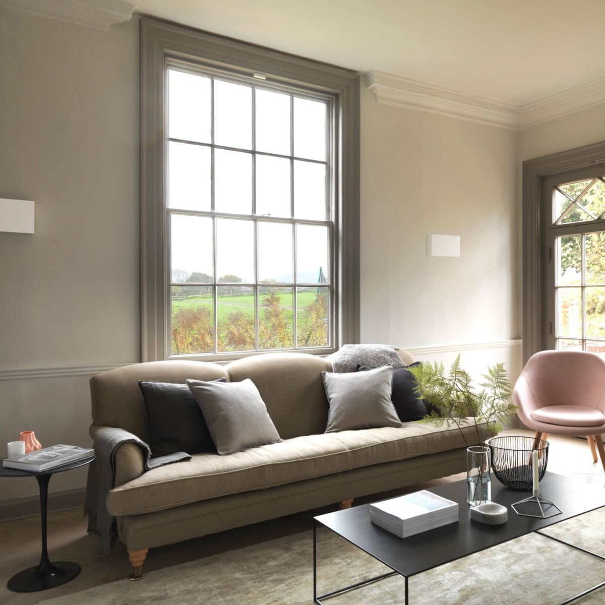 Living room with a beige sofa, black coffee table, and a large window overlooking a green field