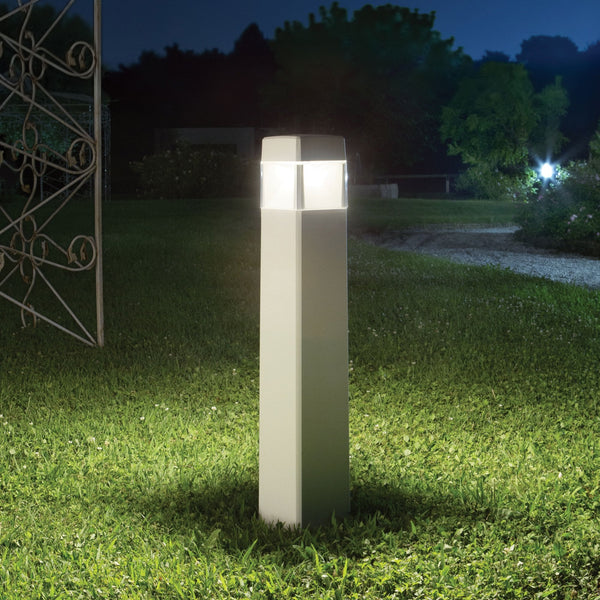 A modern outdoor bollard light illuminating a garden path at night.
