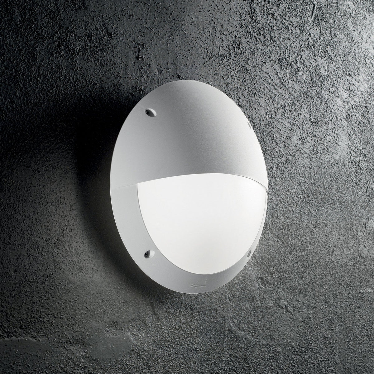 A round, white outdoor wall light casting a glow downwards against a dark, textured wall.