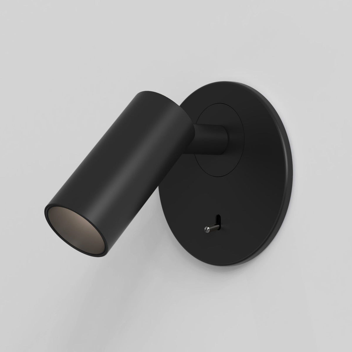 Black wall-mounted spotlight with a cylindrical head and a small toggle switch on the circular base