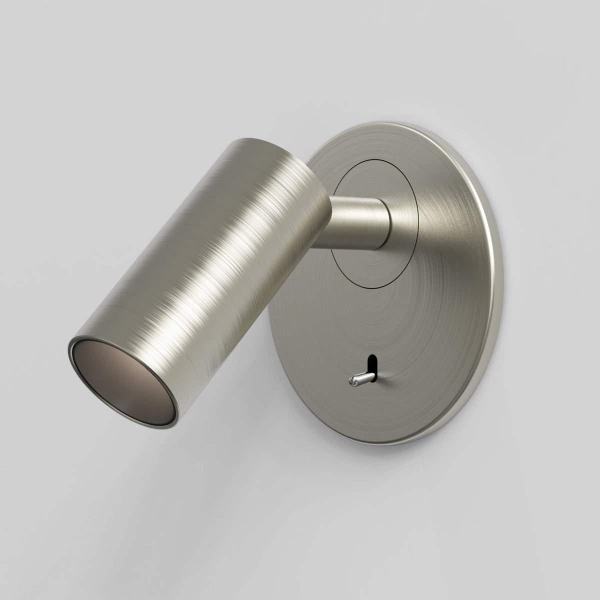 Brushed nickel wall-mounted light fixture with a cylindrical head angled downwards and a small toggle switch