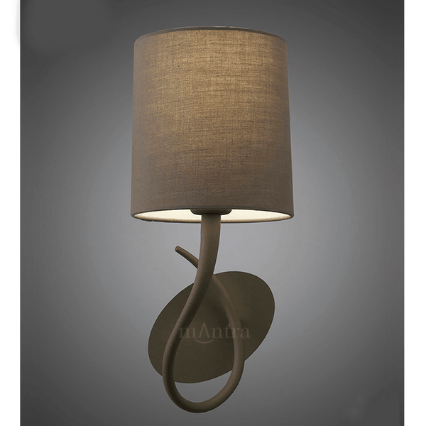 Brown wall light with a cylindrical fabric shade, casting a warm glow.