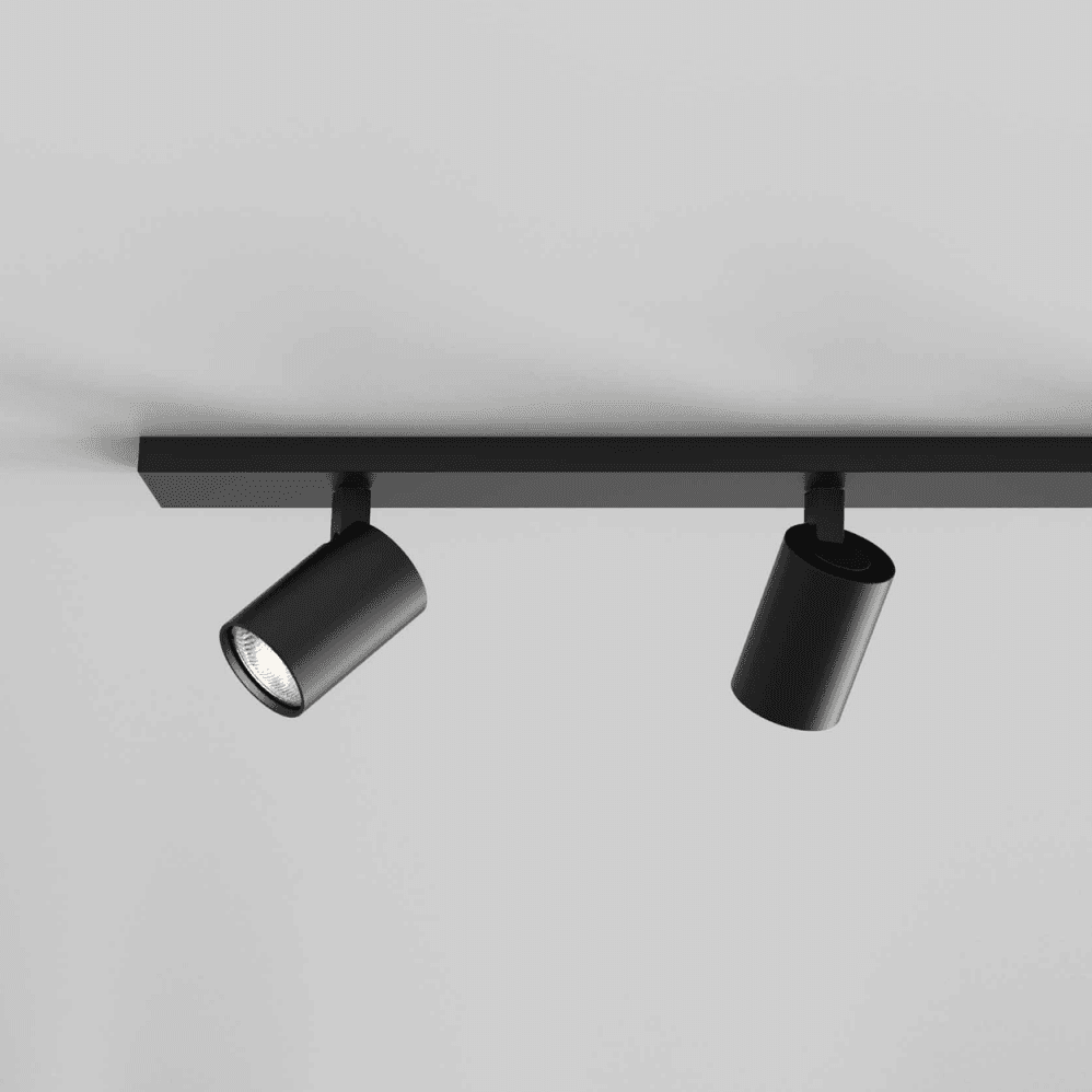 Two black cylindrical track lights on a black track, one illuminated