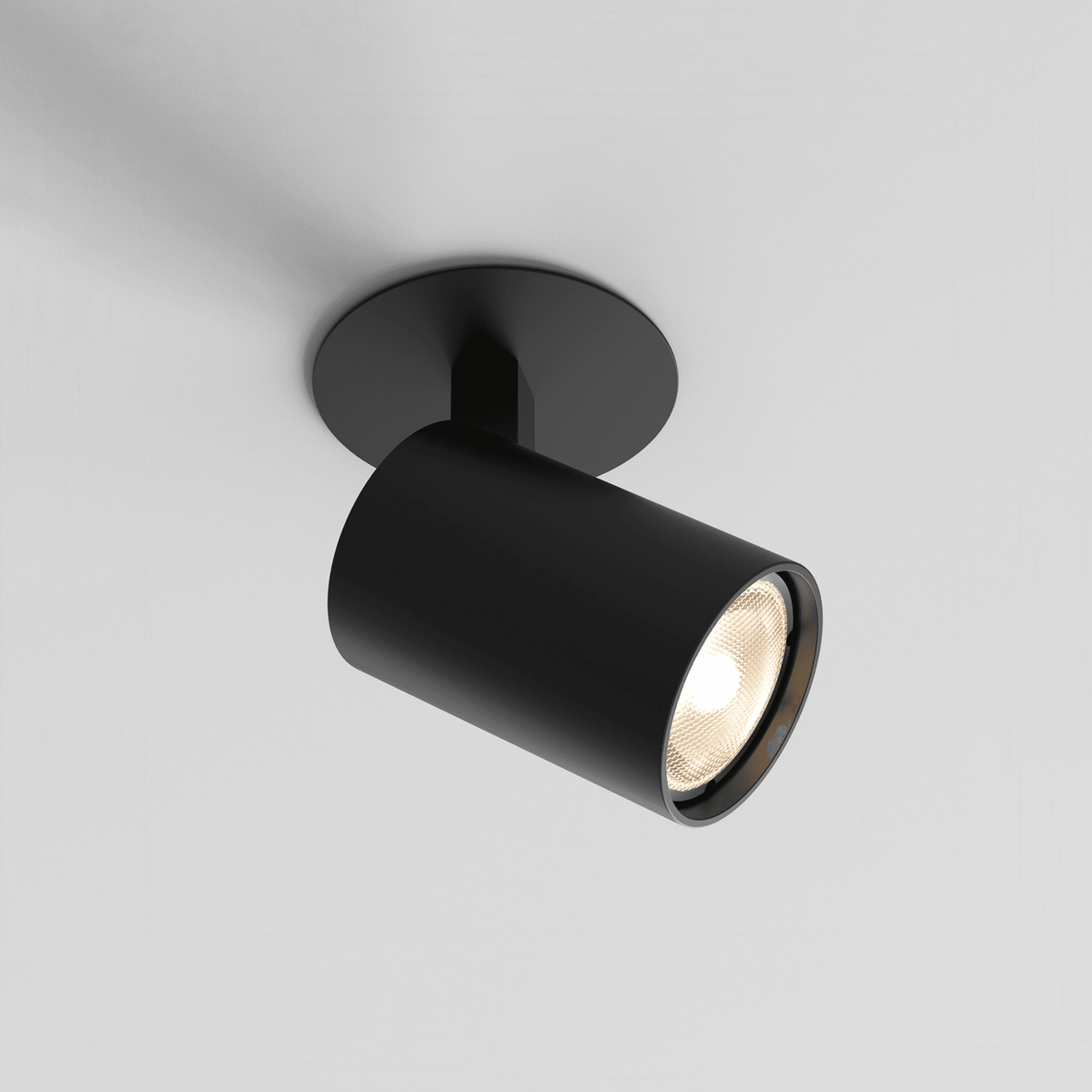 Black cylindrical ceiling spotlight with a warm white bulb