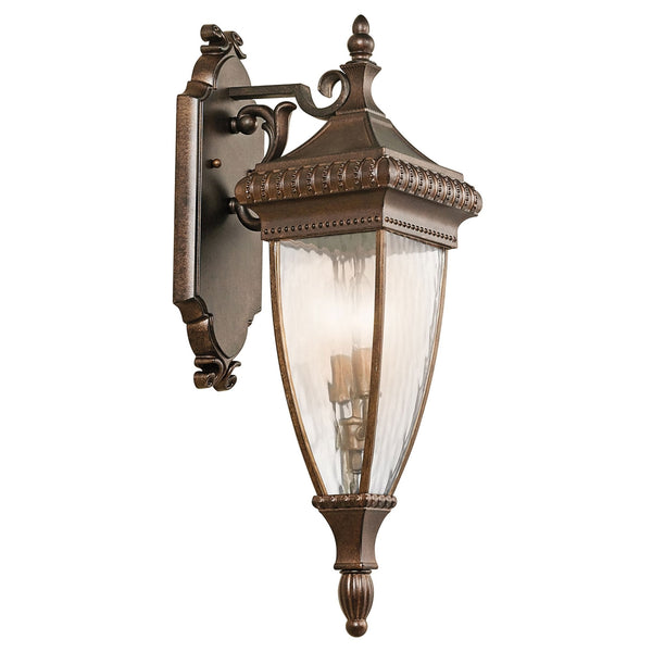 An ornate bronze outdoor wall light with fluted glass, viewed from the front-left.