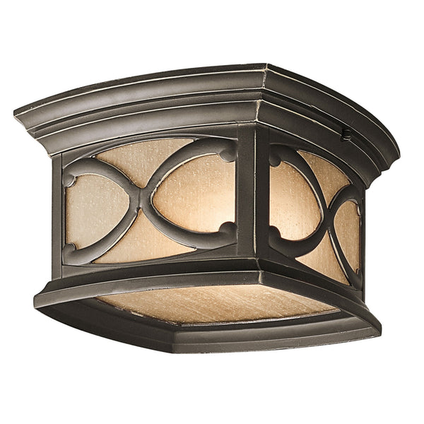A close-up of a bronze flush mount outdoor light with intricate glass panels.
