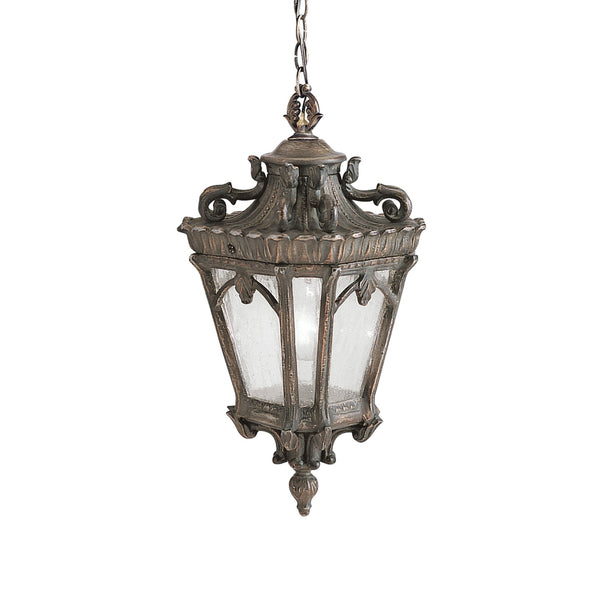 An ornate bronze hanging lantern, designed for outdoor use, casting a warm glow.