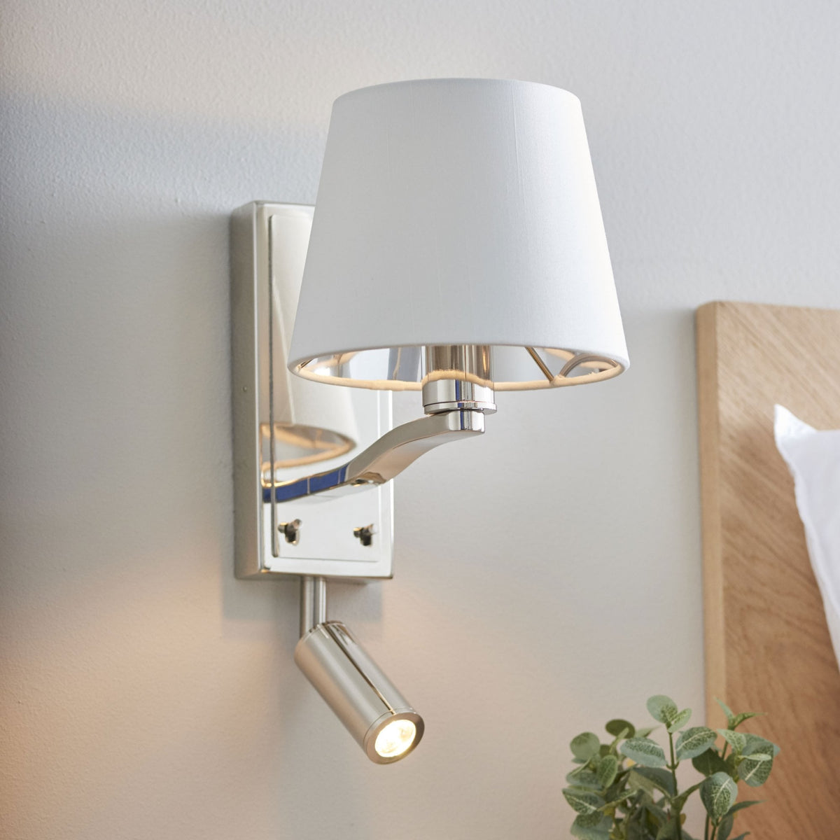 Polished nickel wall light with a white fabric shade and an adjustable reading light.
