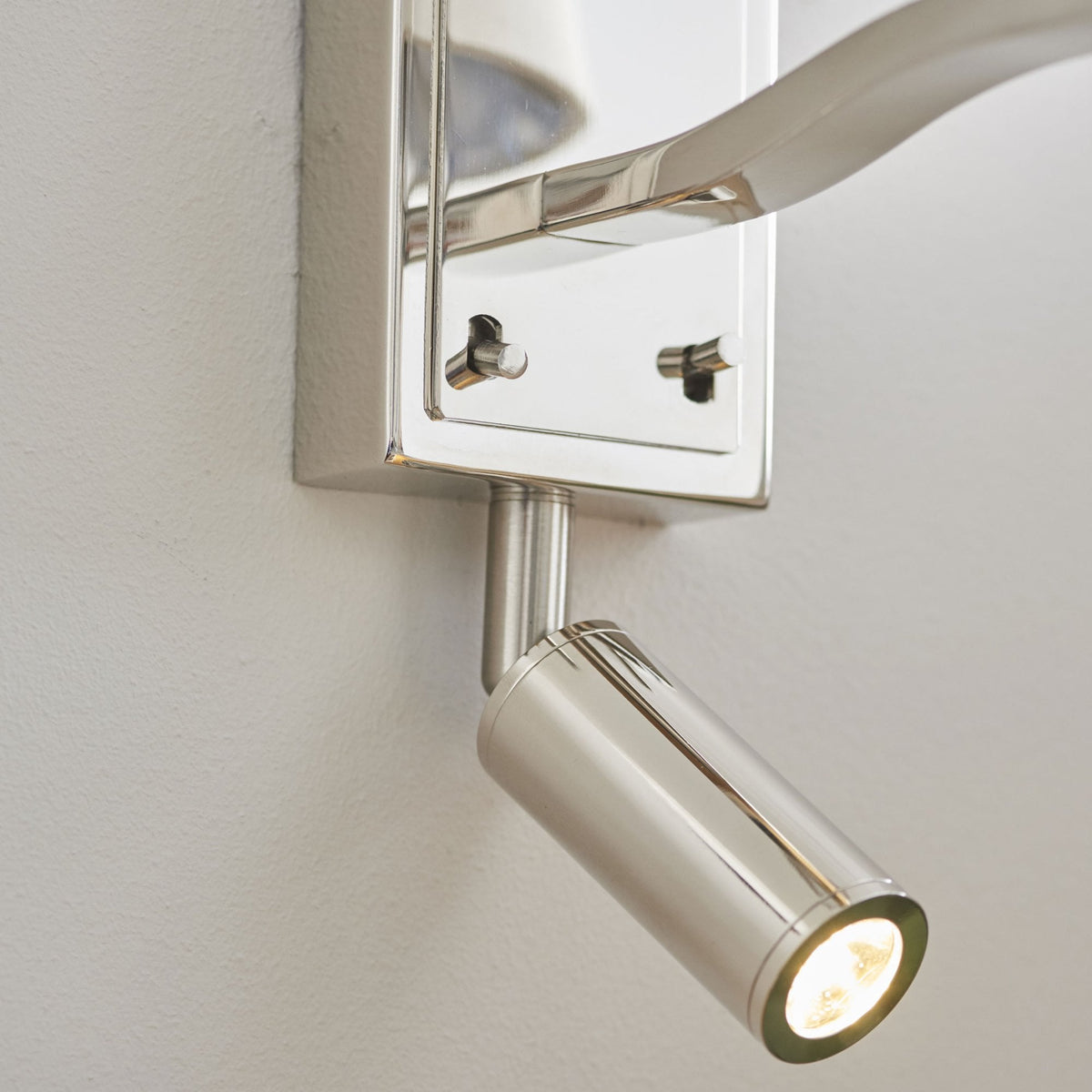 Close-up of the adjustable reading light on a polished nickel wall light.