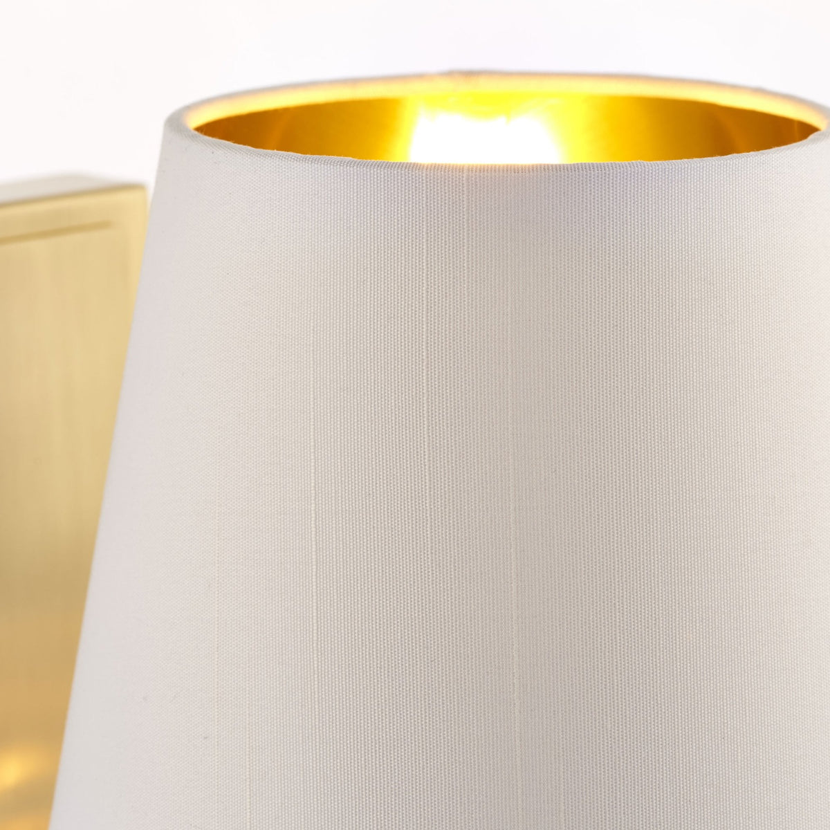 Close-up of the white fabric lampshade with a golden interior, showing the warm light from within.