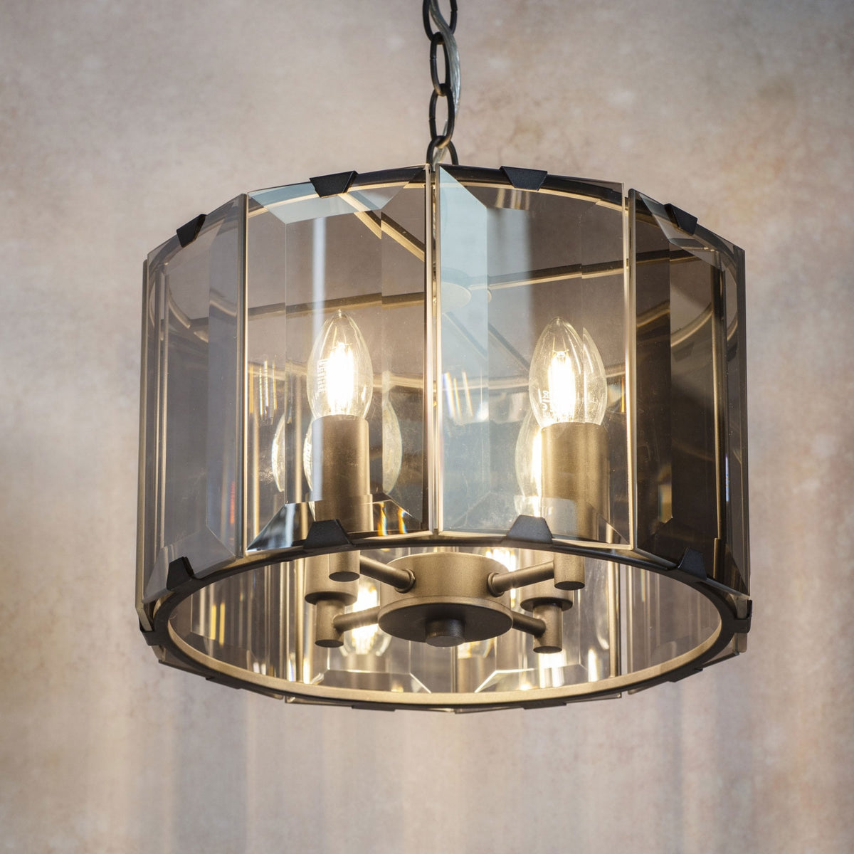 A close-up of a pendant light with a faceted glass shade and three exposed bulbs.