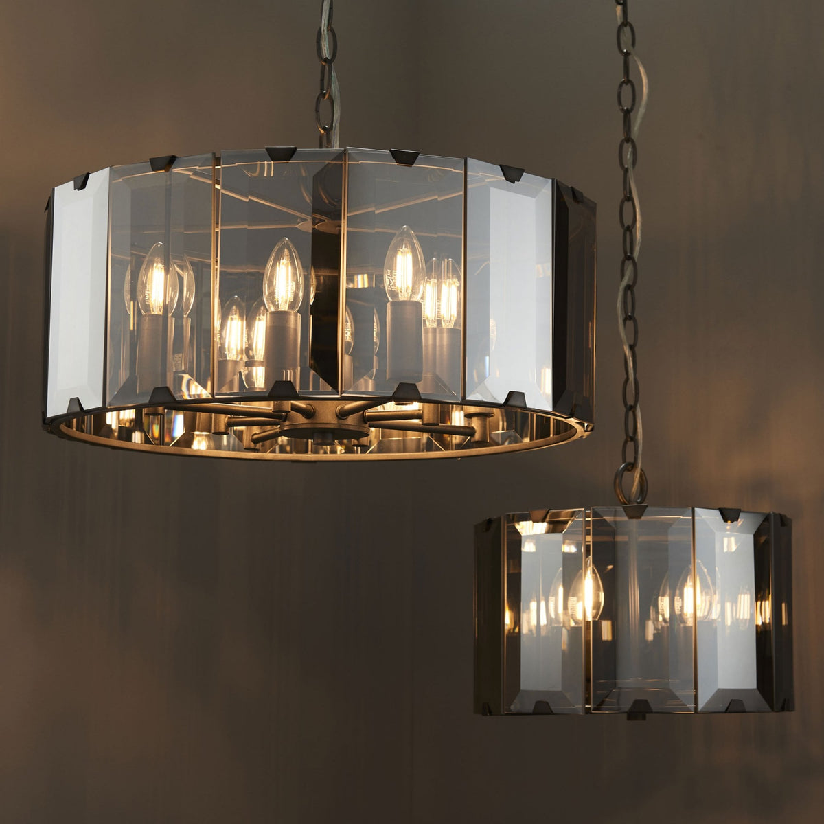 Two pendant lights, one larger and one smaller, both with faceted glass shades and exposed bulbs.