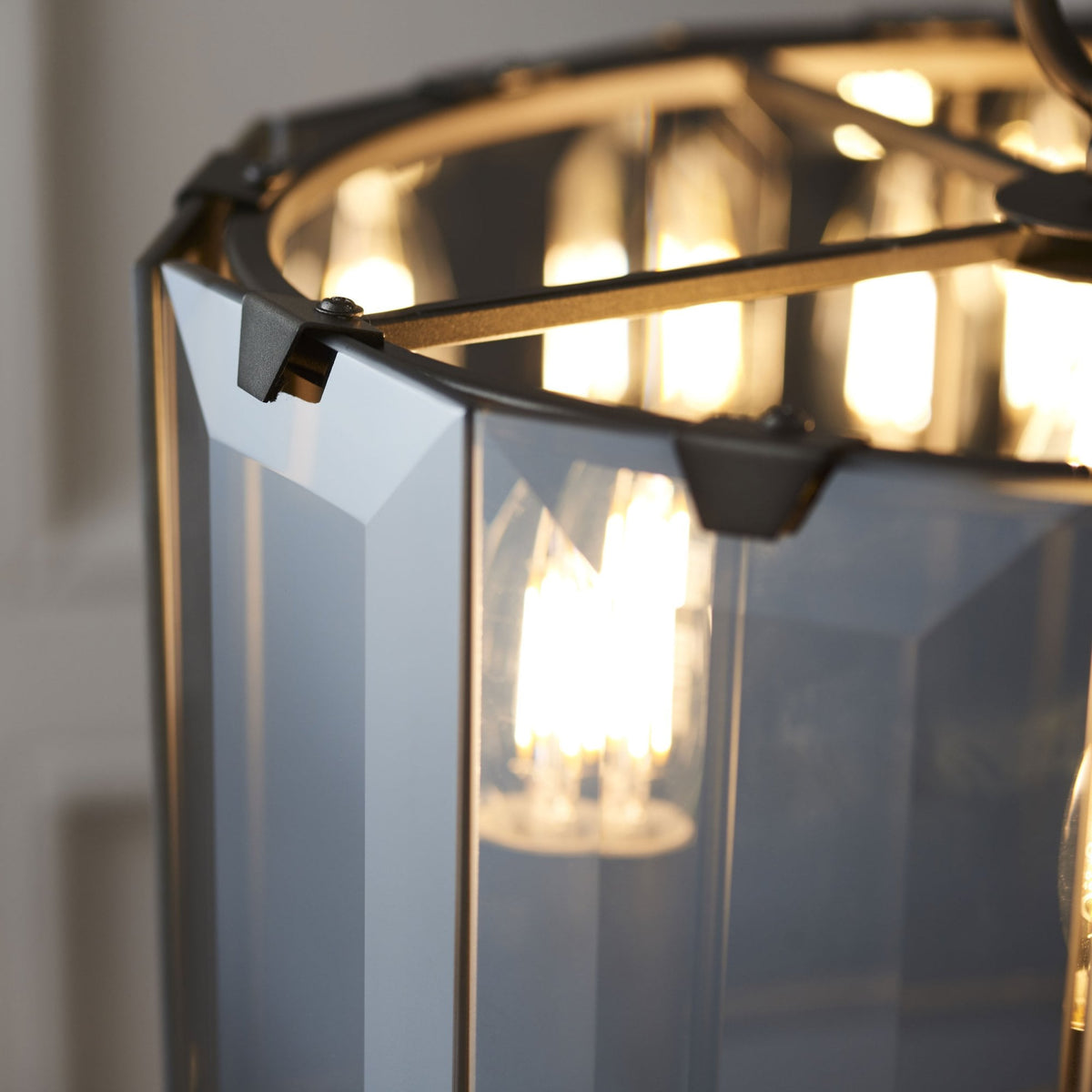 A detailed view of the faceted glass shade and an illuminated bulb of a pendant light.
