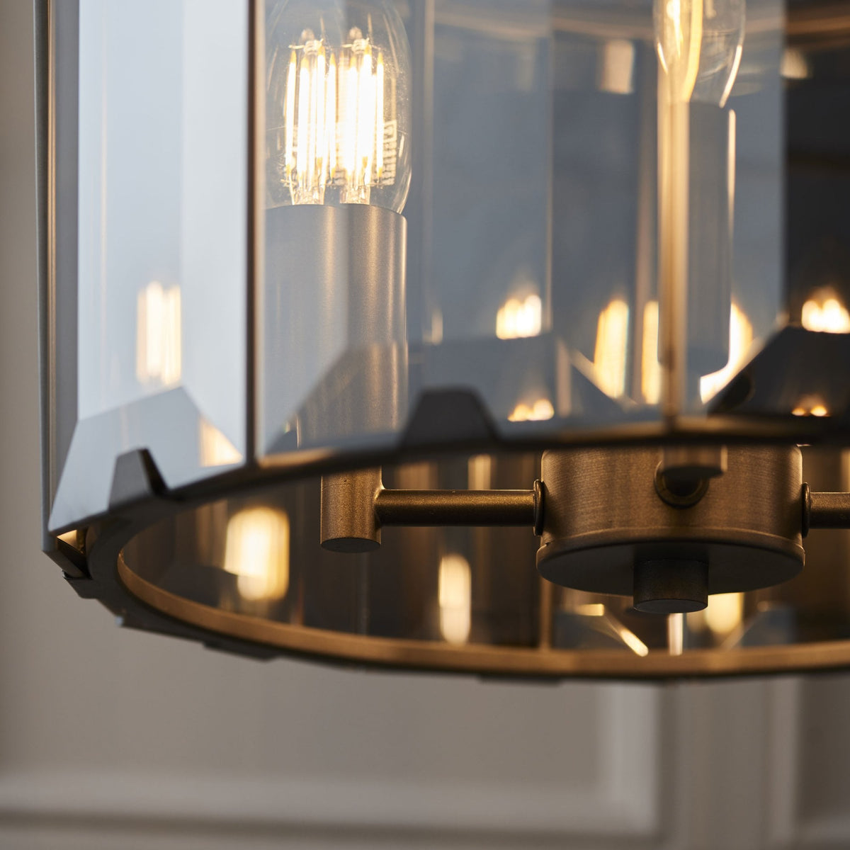 A close-up of the bottom of a pendant light, showing the metal frame and illuminated bulbs within the faceted glass.