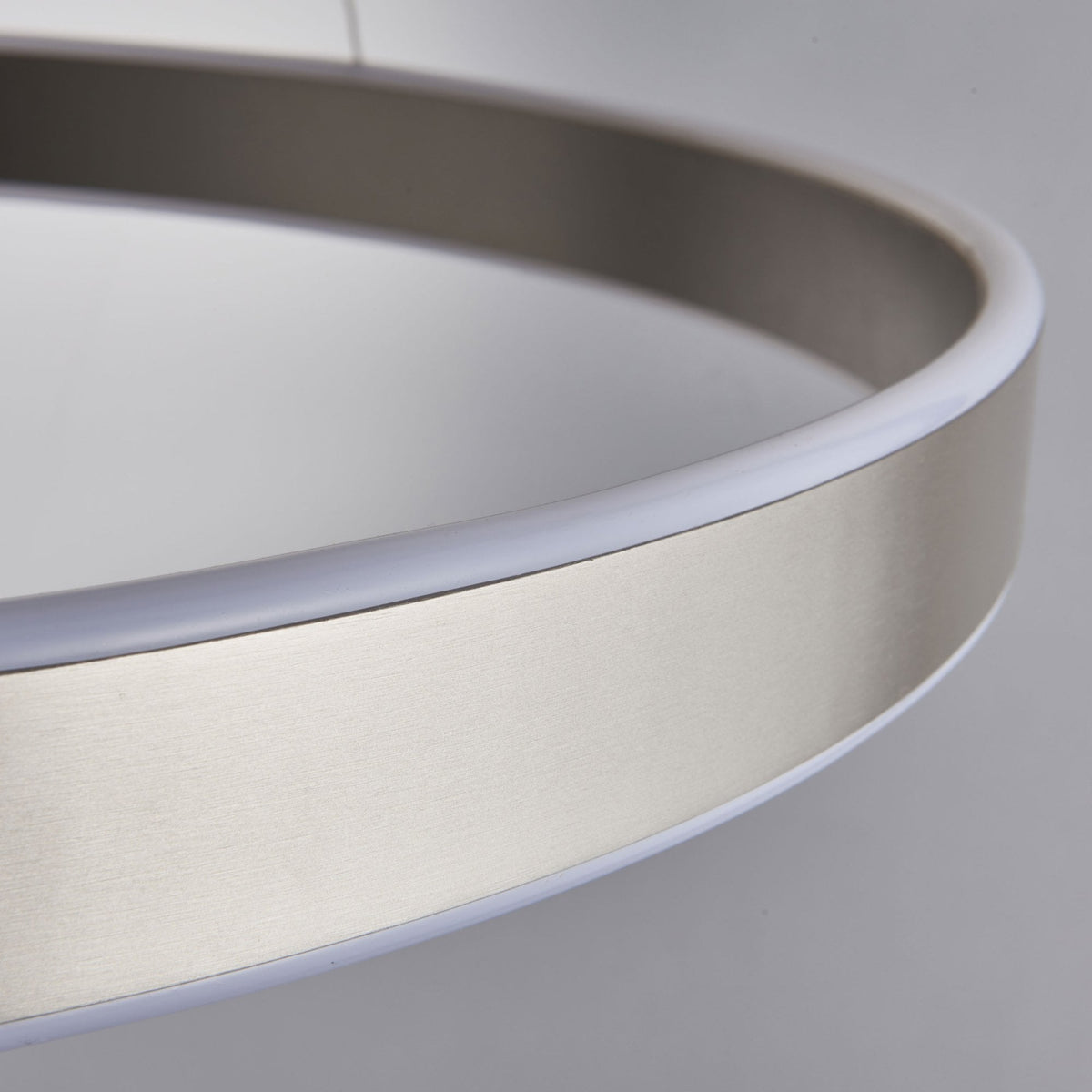 Detailed view of the brushed nickel finish and illuminated diffuser on the edge of a circular LED pendant light.