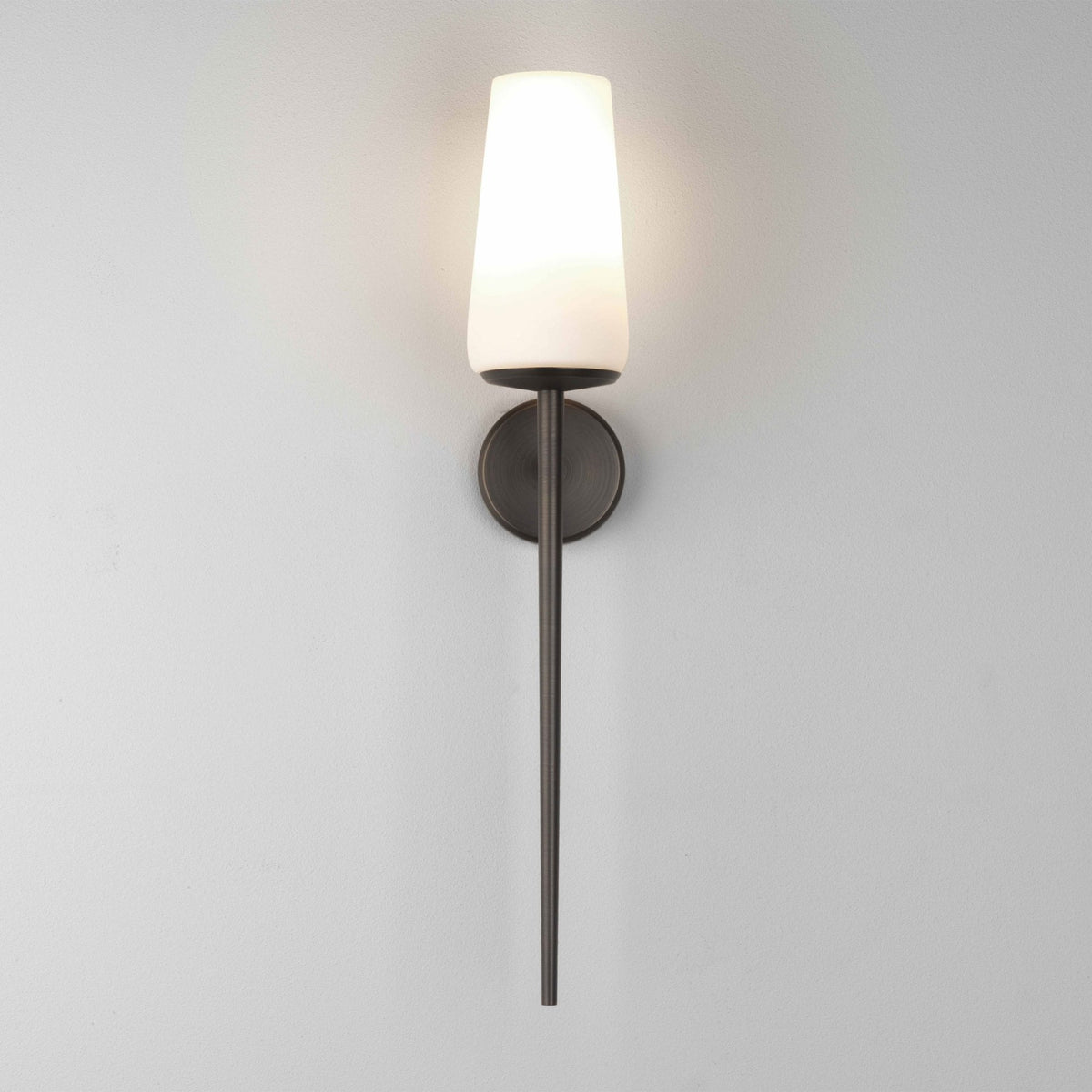 Wall light with a white conical shade and a dark bronze finish on a white wall