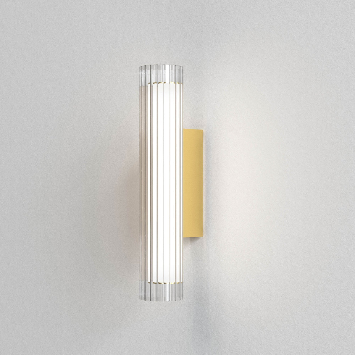 Vertical fluted glass wall light with a gold backplate