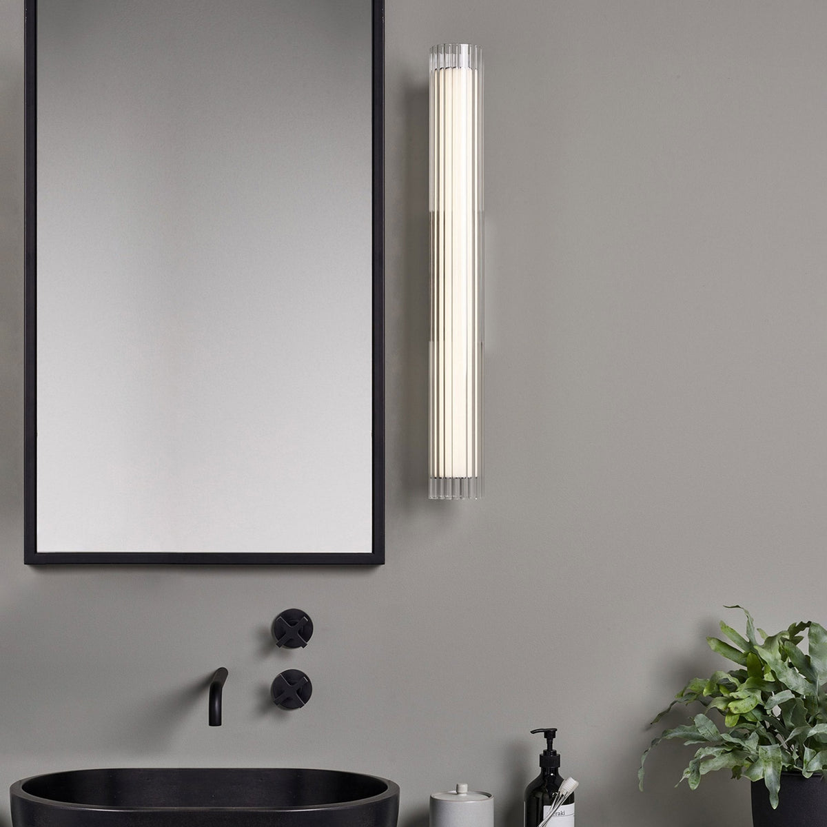 Bathroom with black framed mirror, black basin, black tapware, and a vertical fluted glass wall light