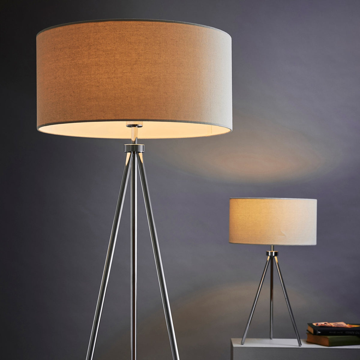 A large tripod floor lamp and a smaller matching table lamp with beige shades and silver legs.