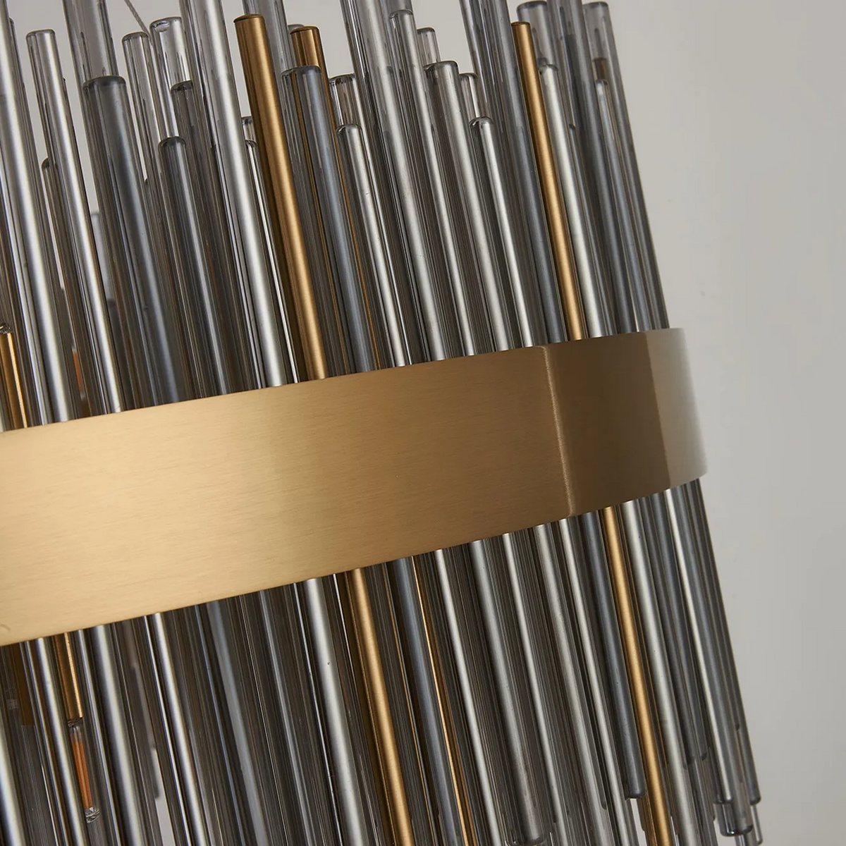 Close up of a modern chandelier with clear and gold glass rods and a gold metal band