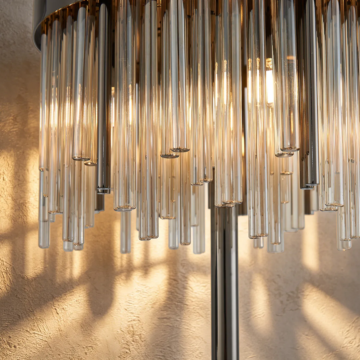 Close up of a modern chandelier with multiple glass tubes and warm light glowing from within
