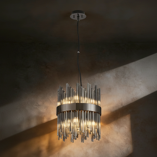 Modern chandelier with multiple glass rods and a dark metal band, illuminated against a textured wall