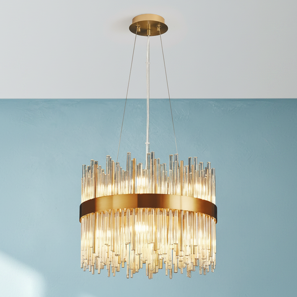 Round gold chandelier with multiple glass rods hanging down, illuminated against a blue wall