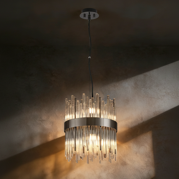 A modern chandelier with clear glass rods and a dark metal band, illuminated against a textured wall