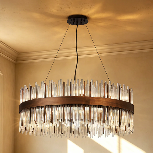 Round chandelier with a bronze frame and clear glass rods hanging from a light-colored ceiling