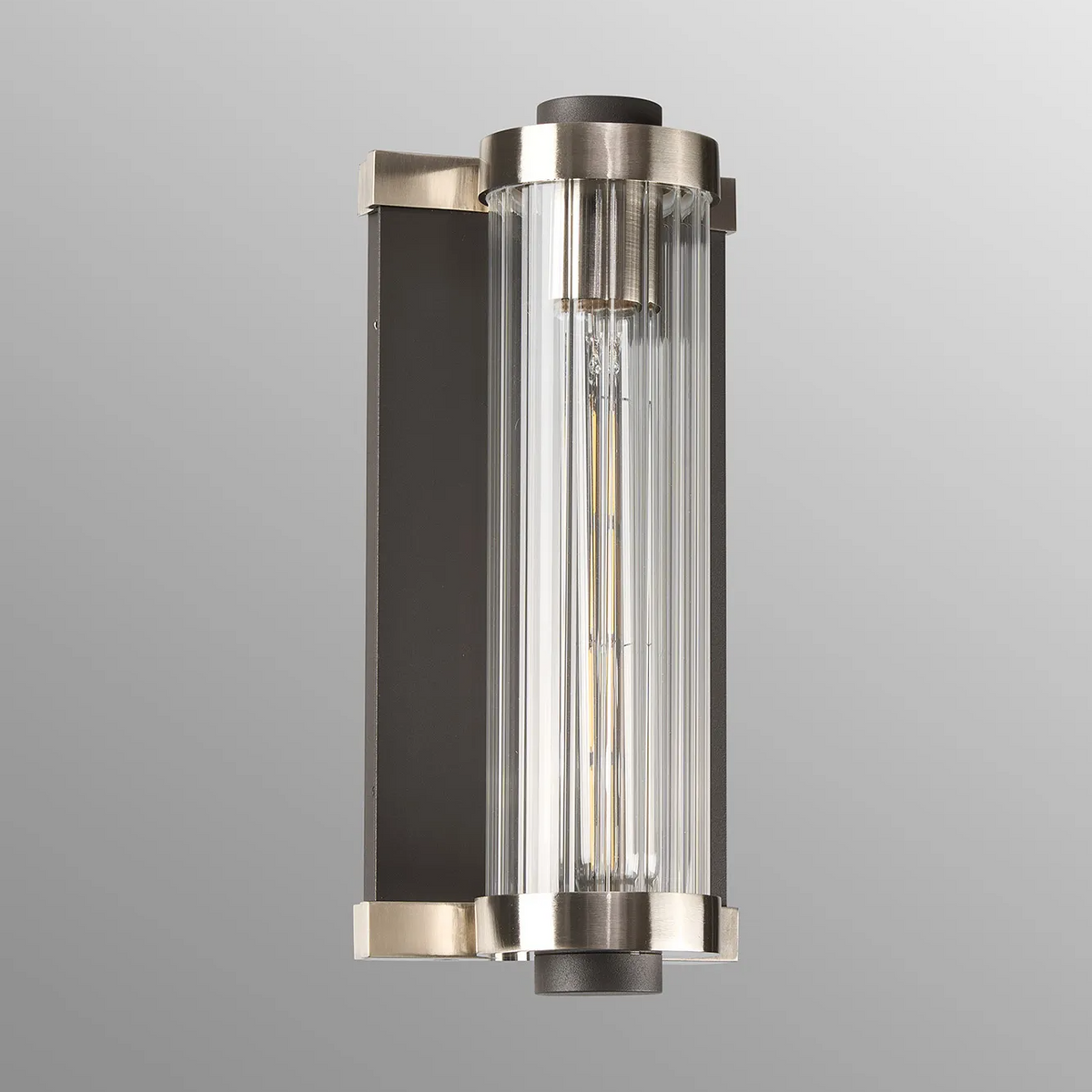 Vertical wall sconce with a dark bronze backplate and brushed nickel accents, clear ribbed glass cylinder
