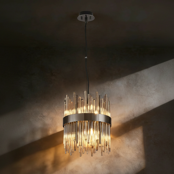 Round chandelier with clear glass rods and a dark metal band, hanging from a black cord against a dark wall