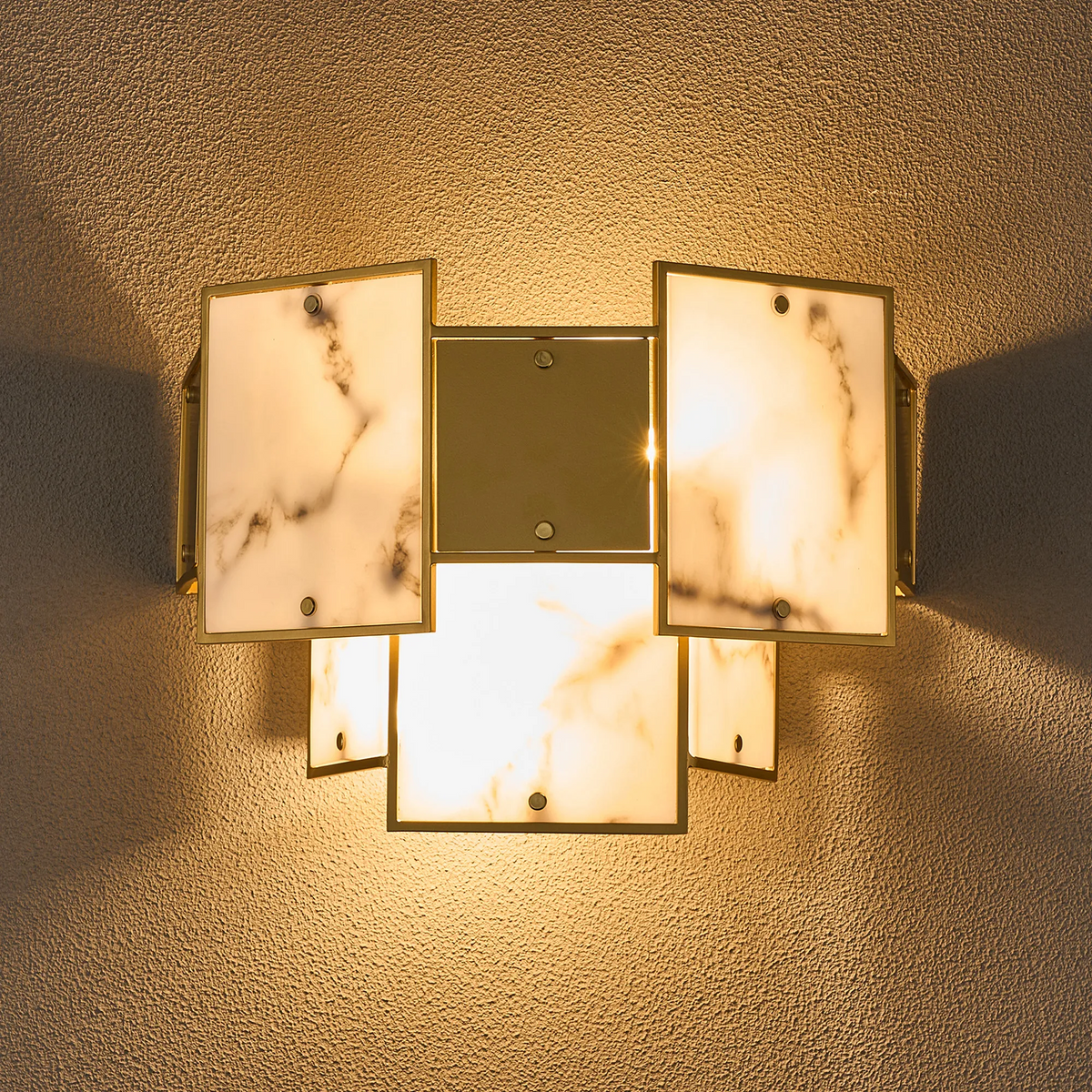 Illuminated wall sconce with gold frame and five rectangular marble-patterned glass panels