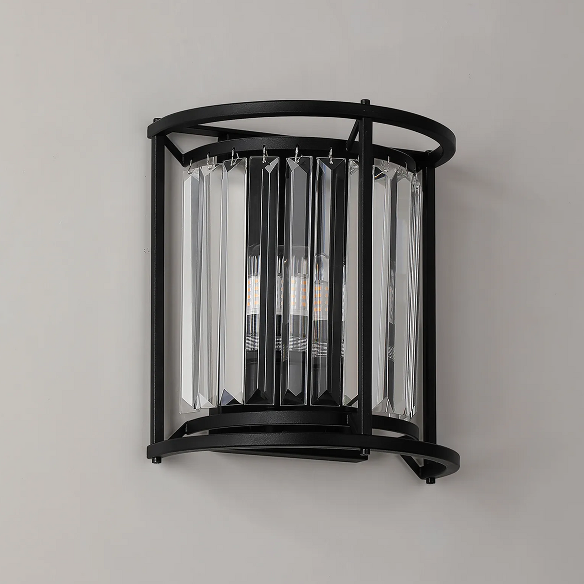 Black metal wall sconce with clear rectangular crystal accents and exposed bulbs
