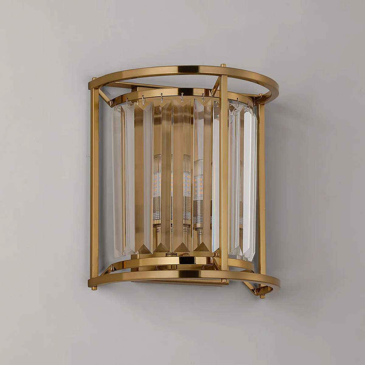 Gold wall sconce with clear crystal panels and exposed bulbs