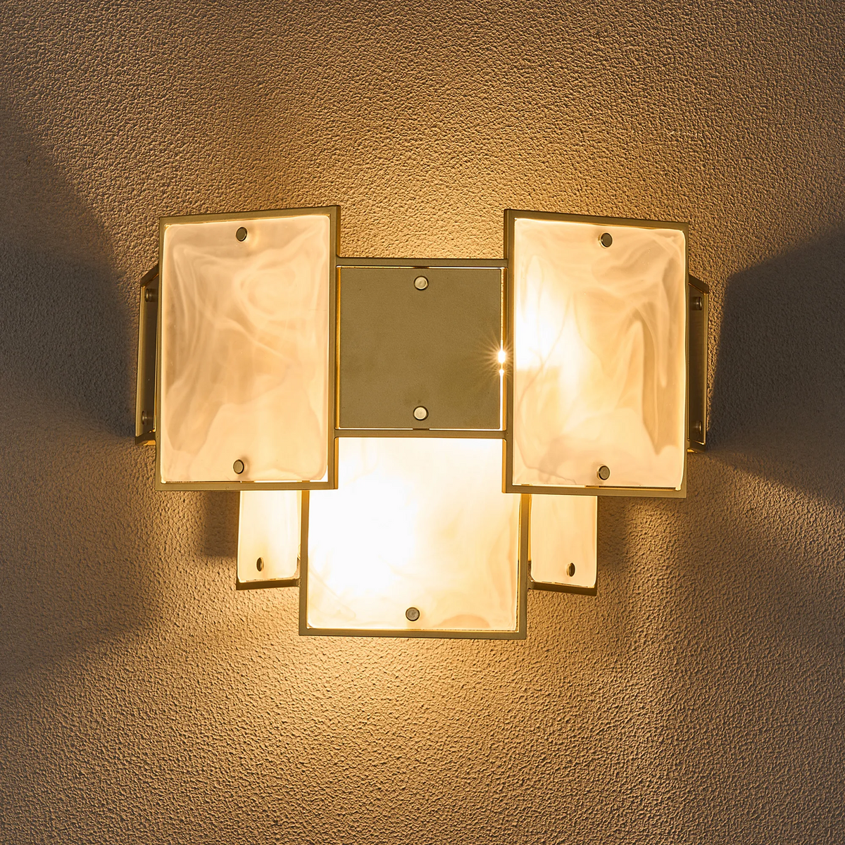 Wall sconce with five rectangular frosted glass panels and a brass frame, illuminated on a textured wall