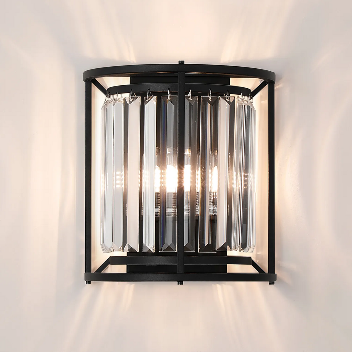 Black metal wall sconce with clear crystal rods and three exposed light bulbs