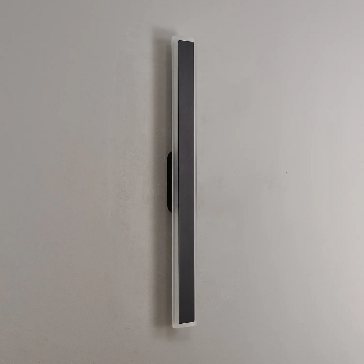 Side view of a vertical black and white wall light on a grey wall