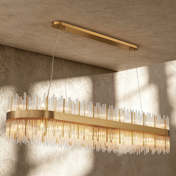 Rectangular chandelier with gold frame and clear glass rods hanging from a textured ceiling