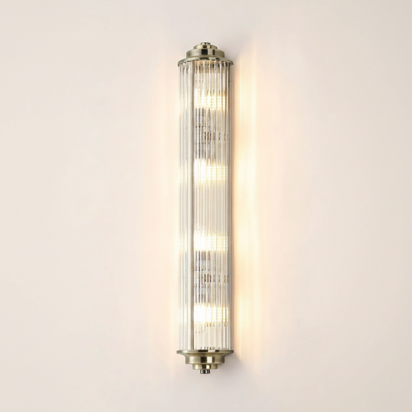 Vertical ribbed glass wall light with brass accents and four illuminated bulbs