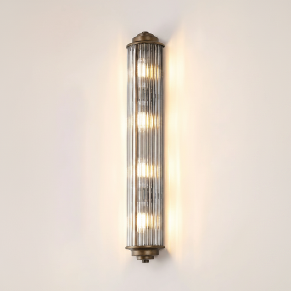 Vertical fluted glass wall sconce with bronze accents and five illuminated bulbs
