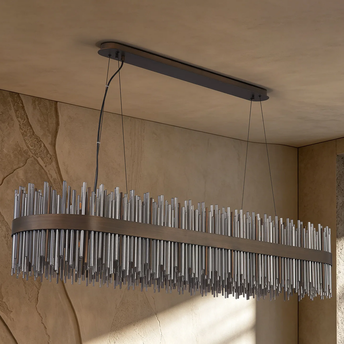 Rectangular chandelier with bronze frame and clear glass rods hanging from a ceiling