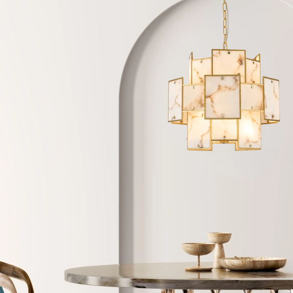 Gold chandelier with square marble panels hanging above a marble table with wooden bowls