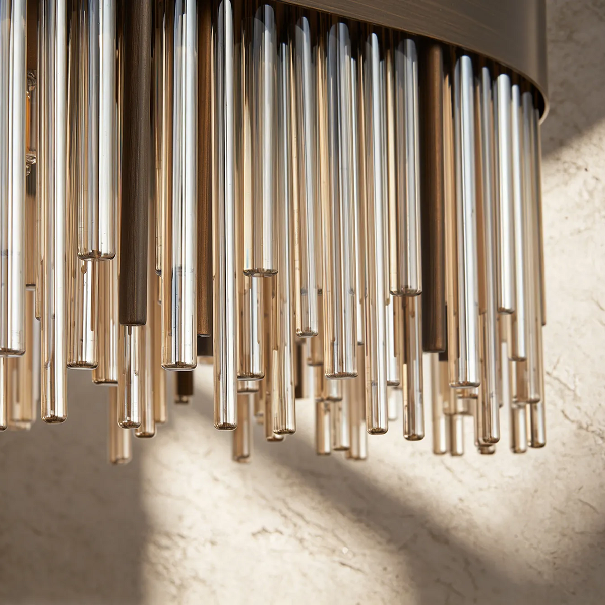Close-up of a wall sconce with multiple vertical glass rods in amber and clear tones