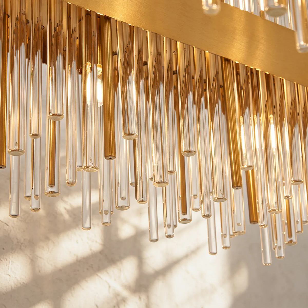 Close up of a gold chandelier with clear glass rods and light bulbs
