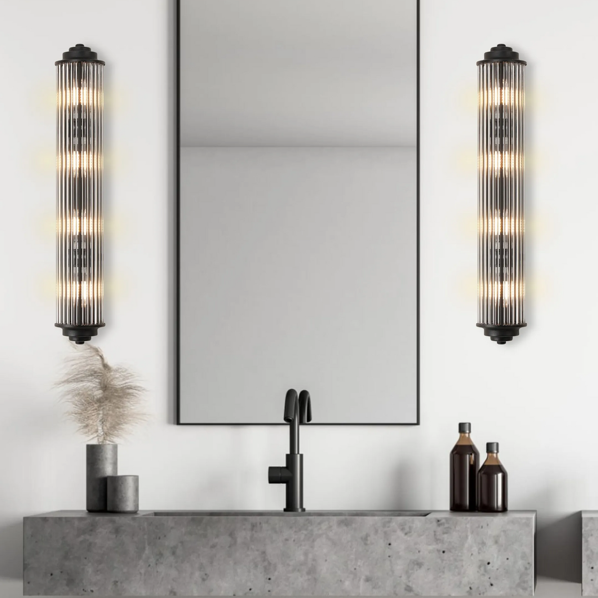 Two vertical ribbed glass wall sconces with black bases flank a mirror above a concrete sink