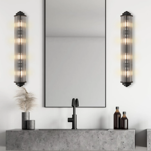 Two vertical ribbed glass wall sconces with black bases flank a mirror above a concrete sink