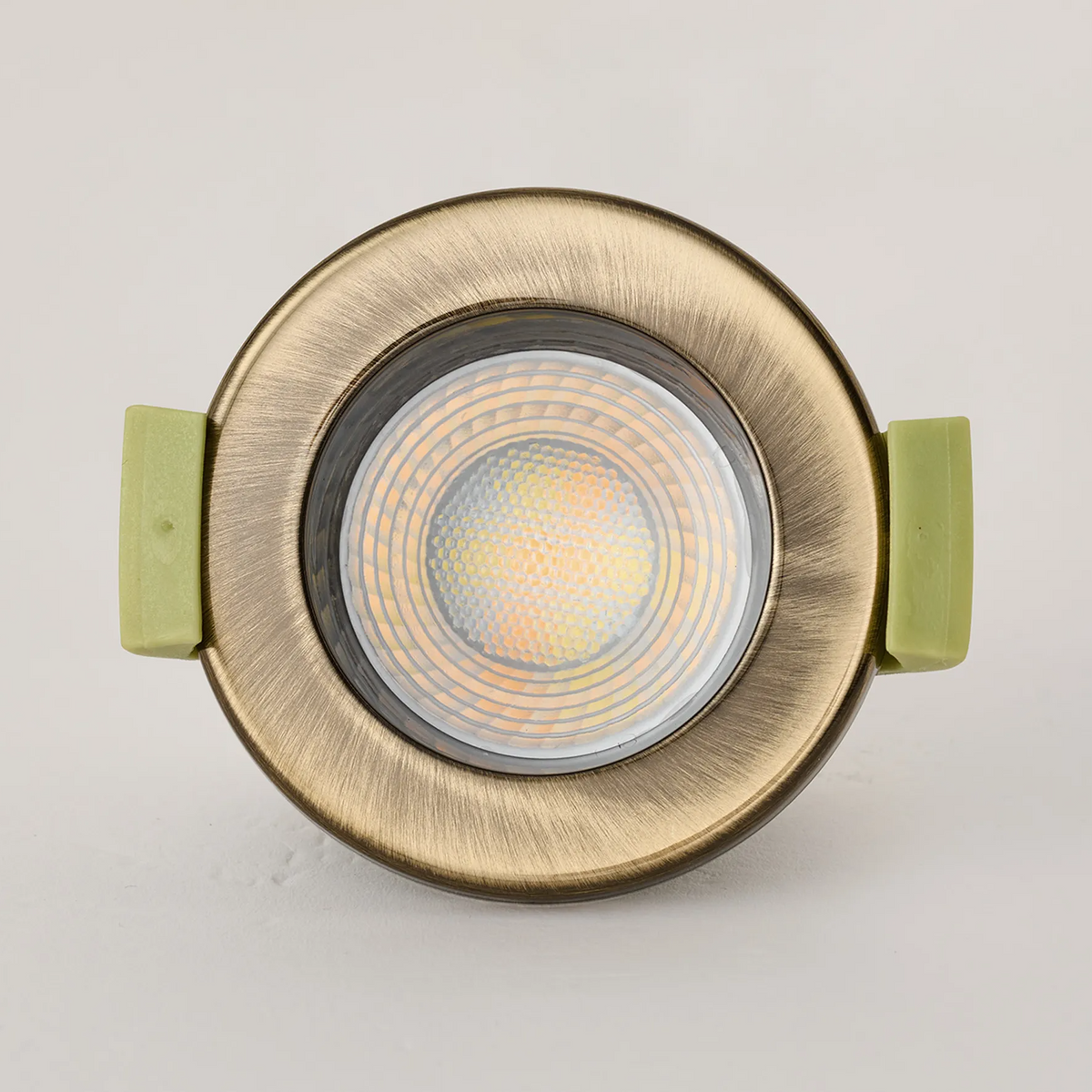 Front view of an antique brass downlight with a warm white light