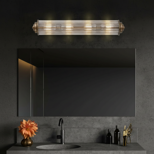 Four light vanity light with ribbed glass shade and antique brass accents over a mirror and concrete sink